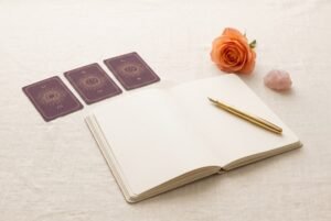 Open journal and gold pen beside purple tarot cards, a peach rose and rose quartz for preparing love tarot questions