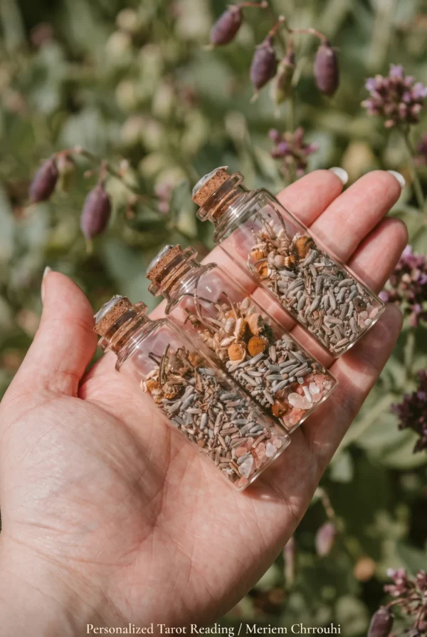 Three corked botanical bottles resting in an open hand against a soft garden background.