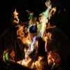 Gold and blue-green flames rising from logs in a dark metal fire basket.