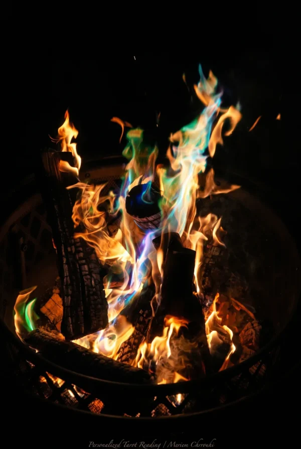 Gold and blue-green flames rising from logs in a dark metal fire basket.
