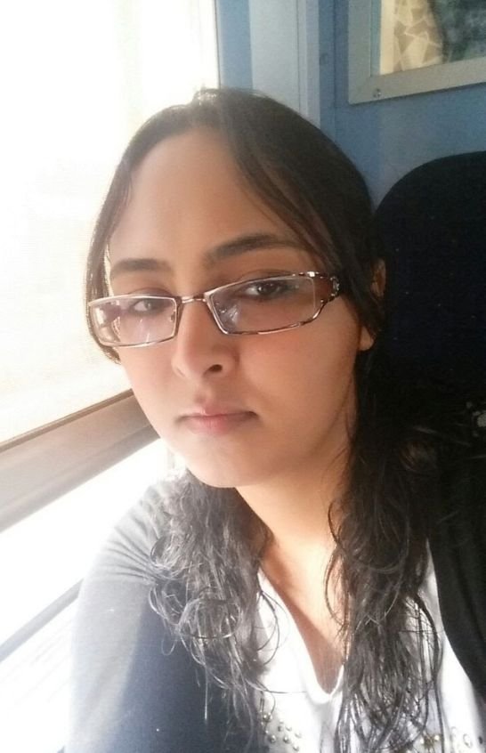Meriem Chrrouhi wearing rectangular glasses beside a sunlit window.