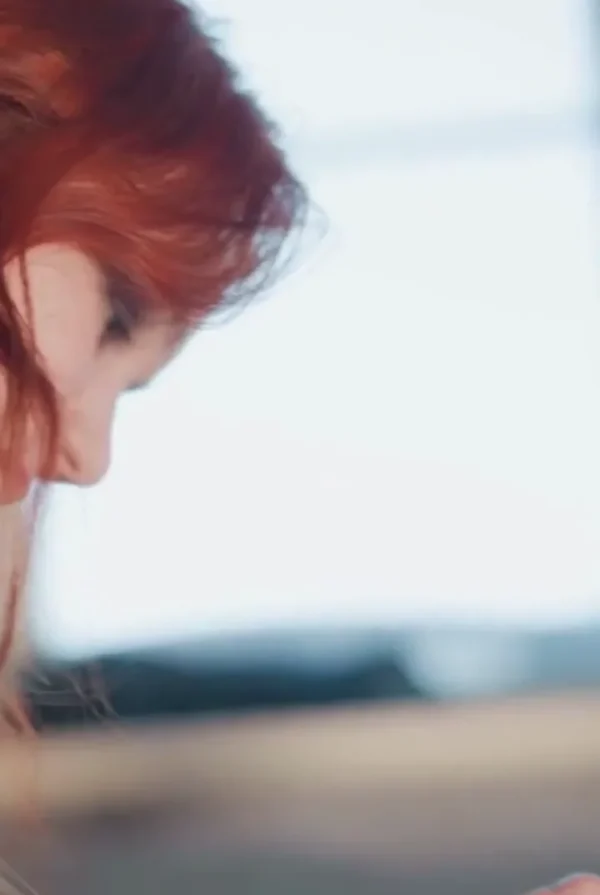 Quiet Personal Reflection — Video Preview | Personalized Tarot Reading Close-up side profile of a red-haired woman looking downward in soft daylight.