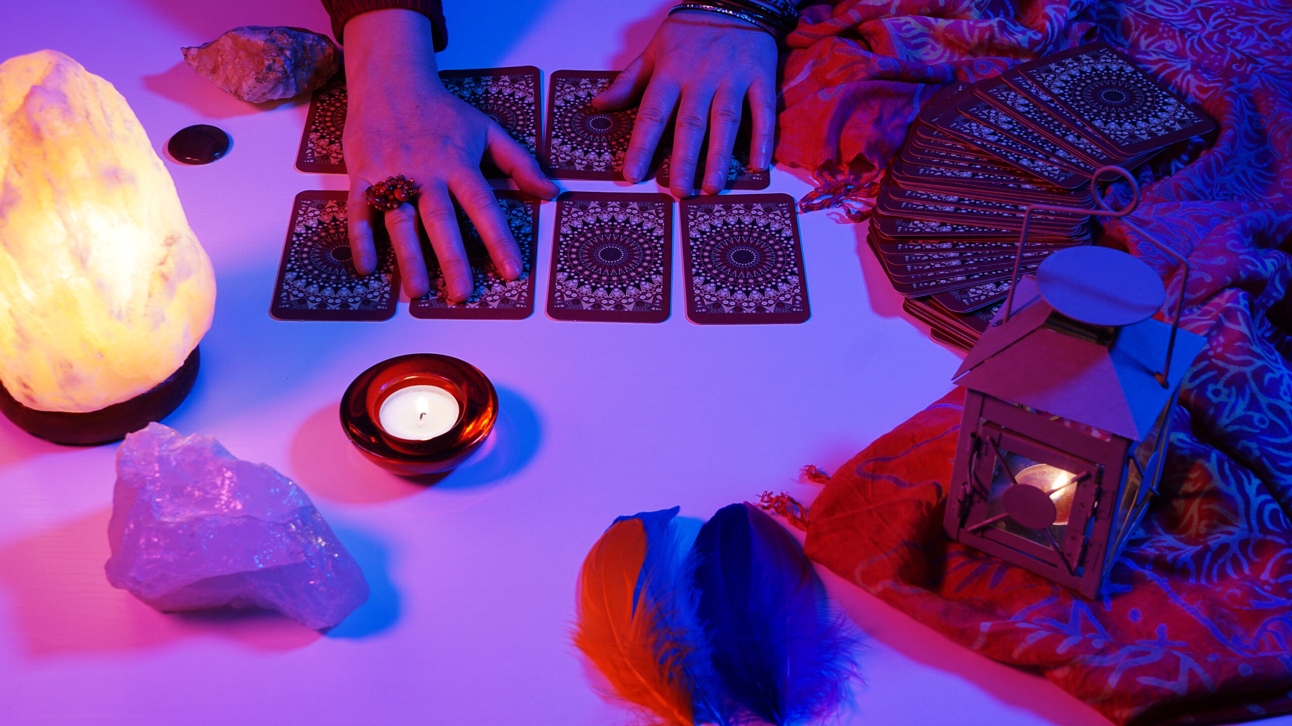 Two hands above tarot cards in blue and pink light, representing a twin flame or soulmate tarot reading