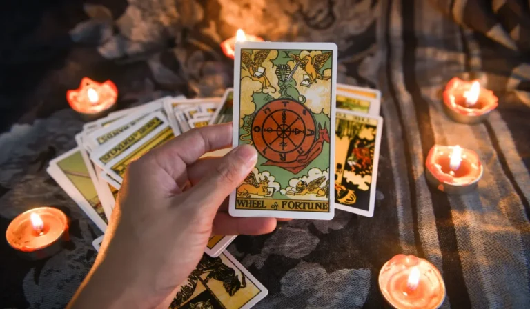 Hand holding tarot cards in warm candlelight