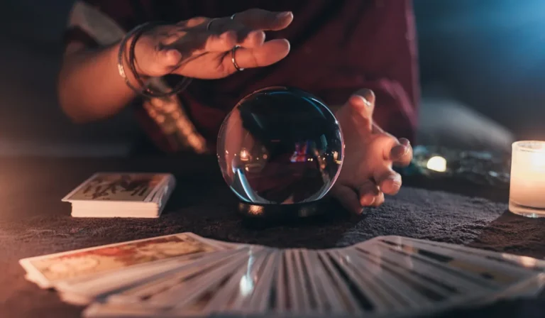 Past life tarot spread with a glowing crystal ball on a dark table