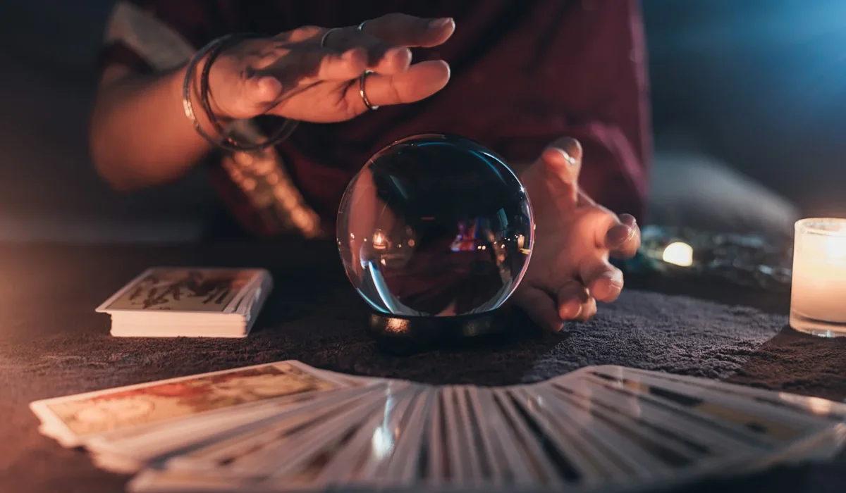 Past life tarot spread with a glowing crystal ball on a dark table