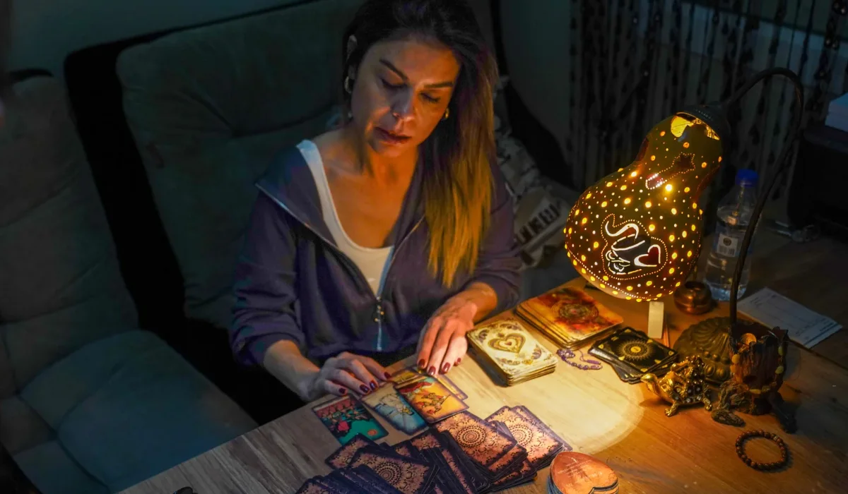 Woman reading tarot cards by lamplight at night