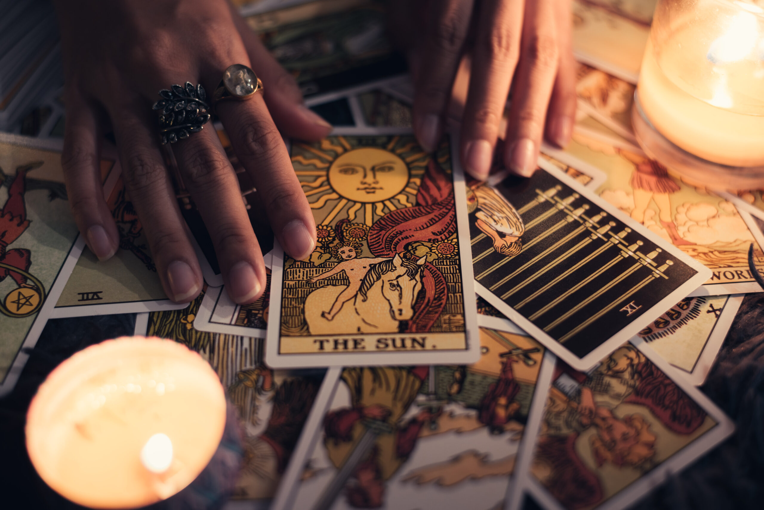 The Sun tarot card in a spread beside lit candles, a hopeful card in career tarot readings
