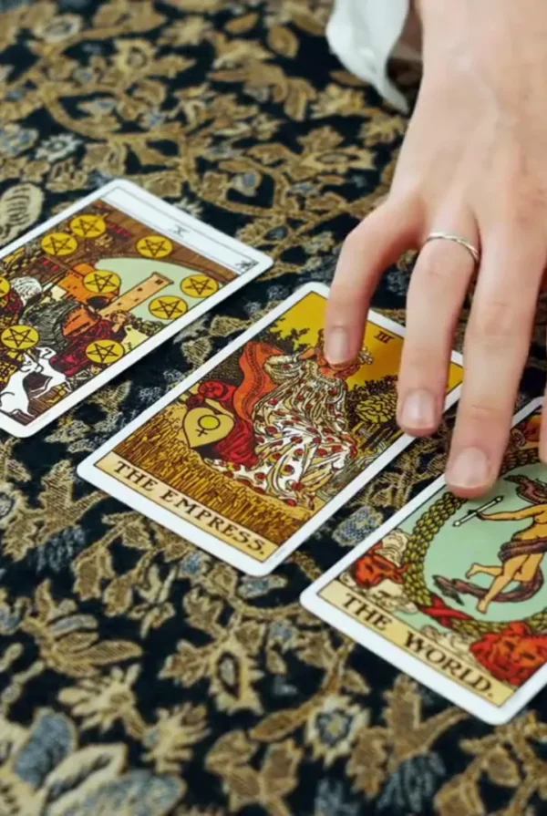 Tarot Card Interpretation — Video Preview | Personalized Tarot Reading Hand resting beside The Empress, The World and Ten of Pentacles tarot cards on patterned fabric.